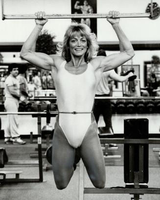 Ranging in, Lynne Pirie dangles from a chinning bar at Gold's Gym