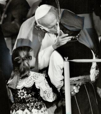 Papal kiss, John Paul bends to kiss a girl dressed in a traditional Polish constume during a rally last night for 55,000 Polish Canadians at Exhibitio(...)
