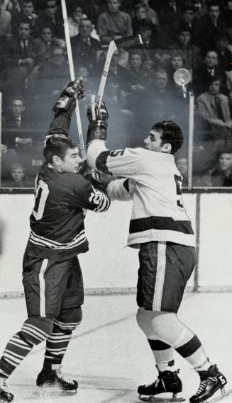 Confrontation on ice. Maple Leafs' Bob Pulford (left) and Brent Hughes of Los Angeles Kings indulge in a bit of fencing as they come face to face at G(...)