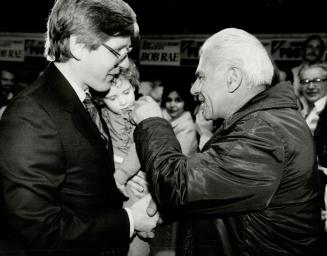 The human touch, Ontario NDP leader Bob Rae smiles at a supporter at Yorkview committee rooms who tickles the cheek of Judith Rae, 31/2, sleepy against Dad's shoulder