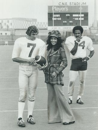 Mrs. Dave Raimey, shown with Argo quarterback Joe Theismann and defensive halfback Dave Raimey, models plaid jacket and cuffed pants