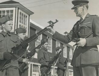 War hero's father: Major F. Georges Triquet, is officer commanding A Coy., 2nd Battalion, Les Fusiliers du St. Laurent (R). Here he is seen holding rifle inspection of a squad from No. 1 platoon