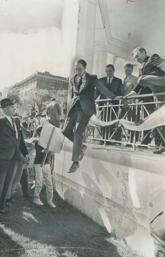 On the hop, Prime Minister Pierre Trudeau vaults over railing of platform into the midst of the crowd after he had finished a campaign speech in Saska(...)