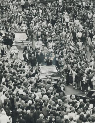 Riding in Triumph through the crowd of 50,000 who jammed Nathan Phillips Square today for a rally in his honor, Prime Minister Pierre Trudeau's motorc(...)