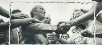Pierre Trudeau is surrounded by hands reaching out to him from all directions