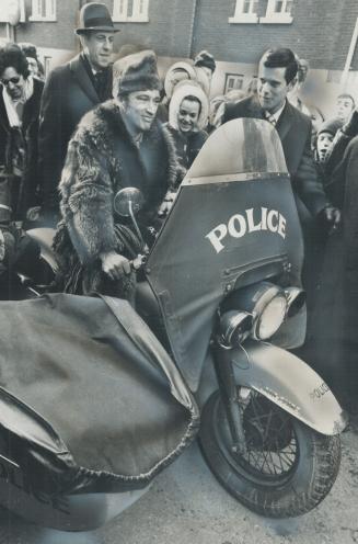 Whooping it up in his raccoon coat at the Quebec Winter Carnival, Prime Minister Pierre Trudeau rides a police motorcycle - one of a weird succession (...)