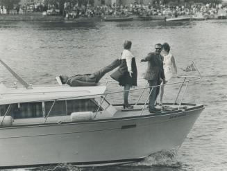 Mock gesture of fear is pantomimed by Prime Minister Pierre Elliott Trudeau as he falls back across roof a cruiser at the Vallyefield, Que., regatta yesterday