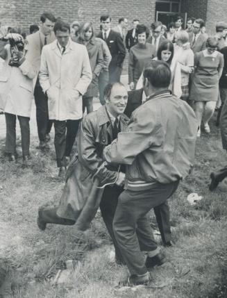 Whoops! Prime Minister Pierre Elliott Trudeau is almost bumped back into a ditch he jumped over as he collides with a bystander as he leaves a Timmins(...)