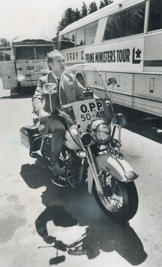 Hamming it up on the hustings. Campaigning Saturday, Prime Minister Pierre Trudeau (left) tries out an Ontario Provincial Police motorcycle on the par(...)