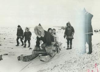 With a kick Pierre Trudeau helps his dog powered sled get started at Pelly Bay, N