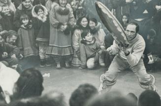 Mukluk-clad Pierre Trudeau beats an Eskimo drum, dances and chants for a delighted audience at Cambridge Bay, N