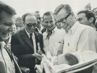 A Tweak for baby: Prime Minister Pierre Elliott Trudeau tweaks the toe of a baby at a Centre Island picnic thrown for Trudeau by the Liberal party yesterday