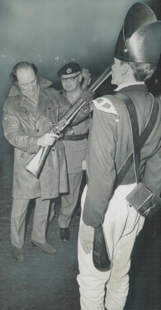 Inspecting the weapons, Prime Minister Pierre Trudeau examines the rifle of a member of honor guard of Queen's York Rangers, at Inn on the Park where (...)