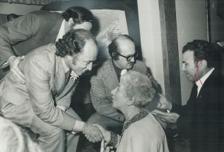 Bending down from the stage, Prime Minister Pierre Trudeau shakes hands with Mary Schneider, a Toronto poet, at the opening of Place Polonaise, a $1 m(...)