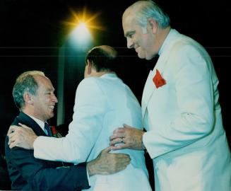 Prime Minister Pierre Trudeau embrases Mark Lelonde as a beaming Kieth Davie waites his turn as Trudeau reaches the podium