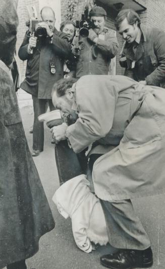Leaving a polling station in Ottawa today after voting, Prime Minister Pierre Trudeau first swings his son, Justin, 10 months old, high in the air, then bends down to let him stand on his hands