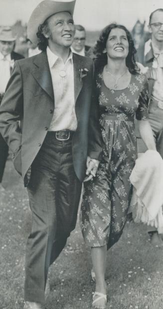 Srolling in the park. Prime Minister Pierre Trudeau and his wife Margaret, look up at at plane towing a banner that reads 'Howdy Pierre' as they strol(...)