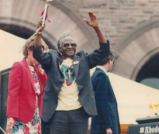 South African Bishop Desmond Tutu waves a peace offering of braided grass at Queen's Park yesterday in response to the 10,000 people at the anti-apartheid rally