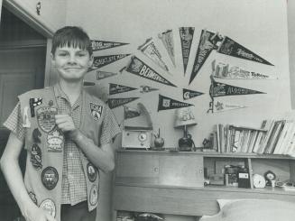 Proud camper, Alan Wallace, 13, displays colorful badges he has collected during National Campers and Hikers Association meets. Pennants decorating th(...)