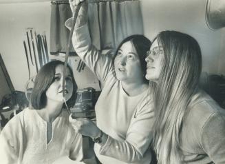 Canada's foremost and most avant-garde woman artist, Joyce Wieland (centre) examines movie film in her darkroom with Judy Steed (right) and Ann Russel(...)