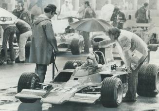 Eppie Wietzes of Thornhill passes umbrella to one of his crew while awaiting start of heat in Formula 5000 at Mosport Saturday. Wietzes wound up as ru(...)