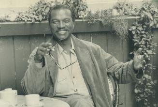 Billy Dee takes tea at Bistro 990 yesterday while being watched by the girls going by