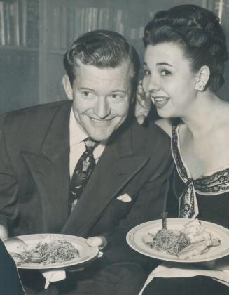 Still Honeymooning, Bill Moss, film producer, and his actress-bride Jane Withers, enjoy a spaghetti dinner at a Hollywood party