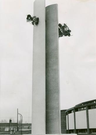 Two tall, parallel, concrete slabs with clusters of metal discs and spokes affixed to upper, ou ...