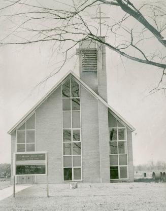 Front of church with steeply pitched roof, and three vertical rows of picture windows. Vented b ...