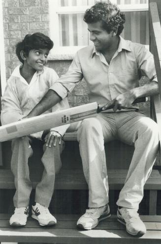 Looking ahead: Gary Rangasamy, who has always dreamed about playing cricket, gets a lesson in how to hold a bat from his brother, Eric, at their uncle's home in Scarborough yesterday