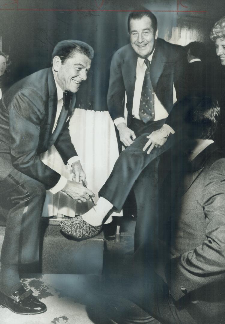Ronald Reagan, former California governor, autographs a cast on the broken leg of Peter Killaley of Mississauga after speaking to a $100-a-plate fund-(...)
