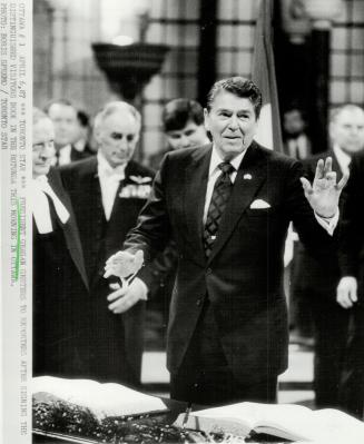 President Reagan gestures to reporters after signing the distinguished visitors book in the rotunda this moring in Ottawa