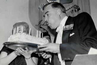 Premier Robarts blows out candles on cake presented at dinner in Kingston