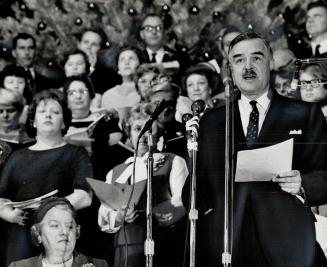 Carols start on a high note. Premier John Robarts gives the Christmas greeting before a choir of 50 civil servants presented Yuletide music at the Par(...)
