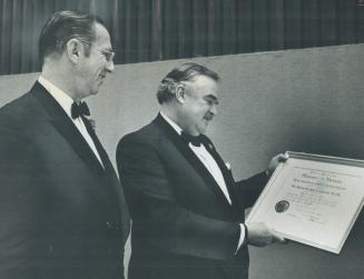 Board of trade honors Robarts. Elected a life member of the Toronto Board of Trade, retiring Ontario Premier John Robarts holds framed scroll presente(...)
