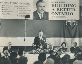 Back to the drawing board. Beneath a banner proclaiming his intention to build a better Ontario, Premier Robarts claims he won't be able to erect as g(...)