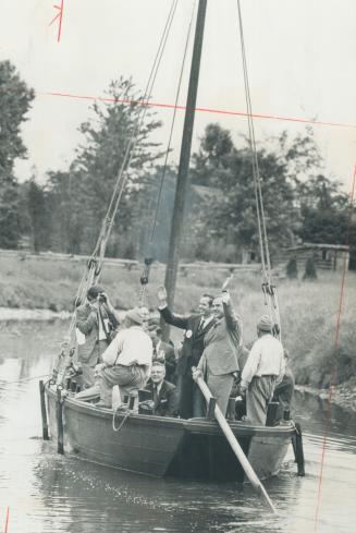At the Helm of a 150-year-old barge, Premier John Robarts and Michigan Governor William Milliken wave to spectators during a tour of Upper Canada Vill(...)