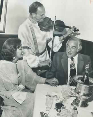 The Robarts are wedded a year. Holding hands while violinist Hans Kaufman serenades them, John Robarts and his wife celebrate their first wedding anni(...)