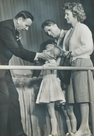 Oral Roberts puts hands on Girl's cheeks, parents look on