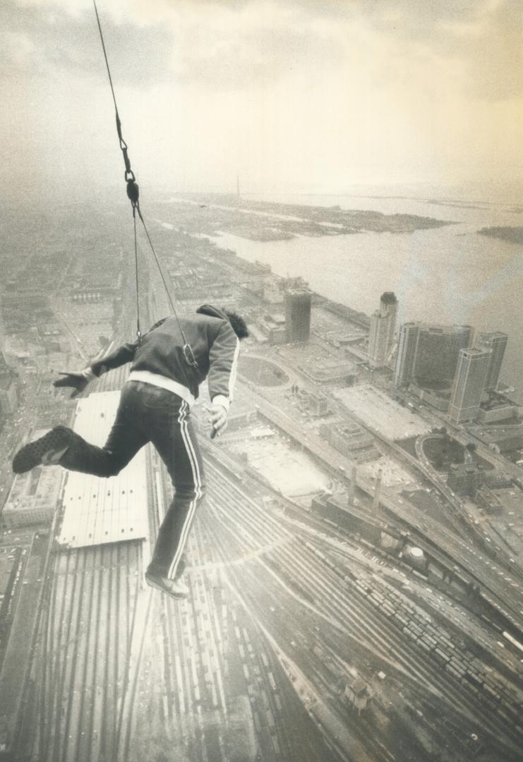 There he goes! Dar Robinson, the California stuntman, flails his arms and legs as he leaps from the 1,100-foot observation level of the CN Tower, with(...)