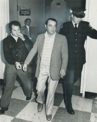 Handcuffed, lathing contractor Cesidio Romanelli (centre) and an employee of his, Natale Luppino of Burlington, leave provincial court yesterday, rema(...)