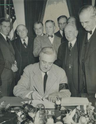 F.D.R. Pens historic declaration of war. Surrounded by Senate leaders, President Roosevelt yesterday grimly signed the formal declaration of war again(...)