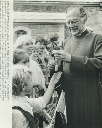 A rose for the primate. A young girl presents a large rose to the Archbishop of Canterbury as he leaves St. James Church
