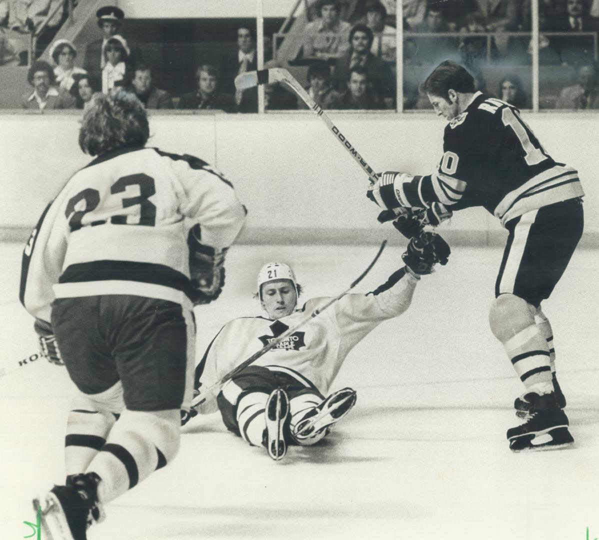 Leafs' Borje Salming closes legs on puck as Boston's Jean Ratelle hovers and teammate Randy Carlyle closes in