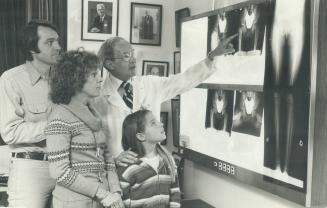 Problem area: Dr. Robert Salter shows x-rays to Bob and Cassandra Greene and daugher Nicole, 9, before surgery