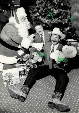 Shack's on Santa's track. Former Toronto Maple Leafs player Eddie Shack, right, is checked by a load of toys for needy kids at a Scarborough Chamber o(...)
