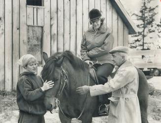 Joseph Bauer gives riding instructions to Mrs. Shirley Trailing at Shadow Creek Stables, north of Toronto. Mrs. Trailing is one of the handicapped who are learning to ride under the sponsorship of the Community Association for the Disabled. Mrs. Joyce Powell, standing left, is one of the volunteers who help with lessons.