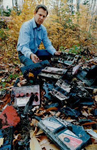 Battery graveyard: Bill Baker examines old batteries found on land he rents from the federal government.
