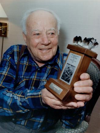 Walter Baker, a prospector for 65 of his 83, years, holds the trophy presented to him by the Prospectors and Developers Association of Canada proclaiming him Prospector of the Year. At left, he pans for gold.
