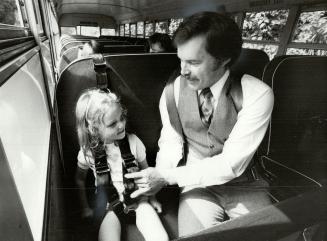 New harness: Gary Barwick of Agincourt has developed new systems of shoulder-lap and shoulder-between-the-leg belts, being tried on by 4-year-old Fiona Daunt, that prevent children from lunging forward and banging their heads.